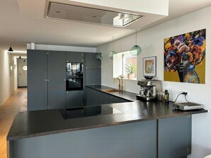 A modern kitchen with a central island, pendant lighting, and a large window. - Converted island ferry with sea access in Stege (Stege)