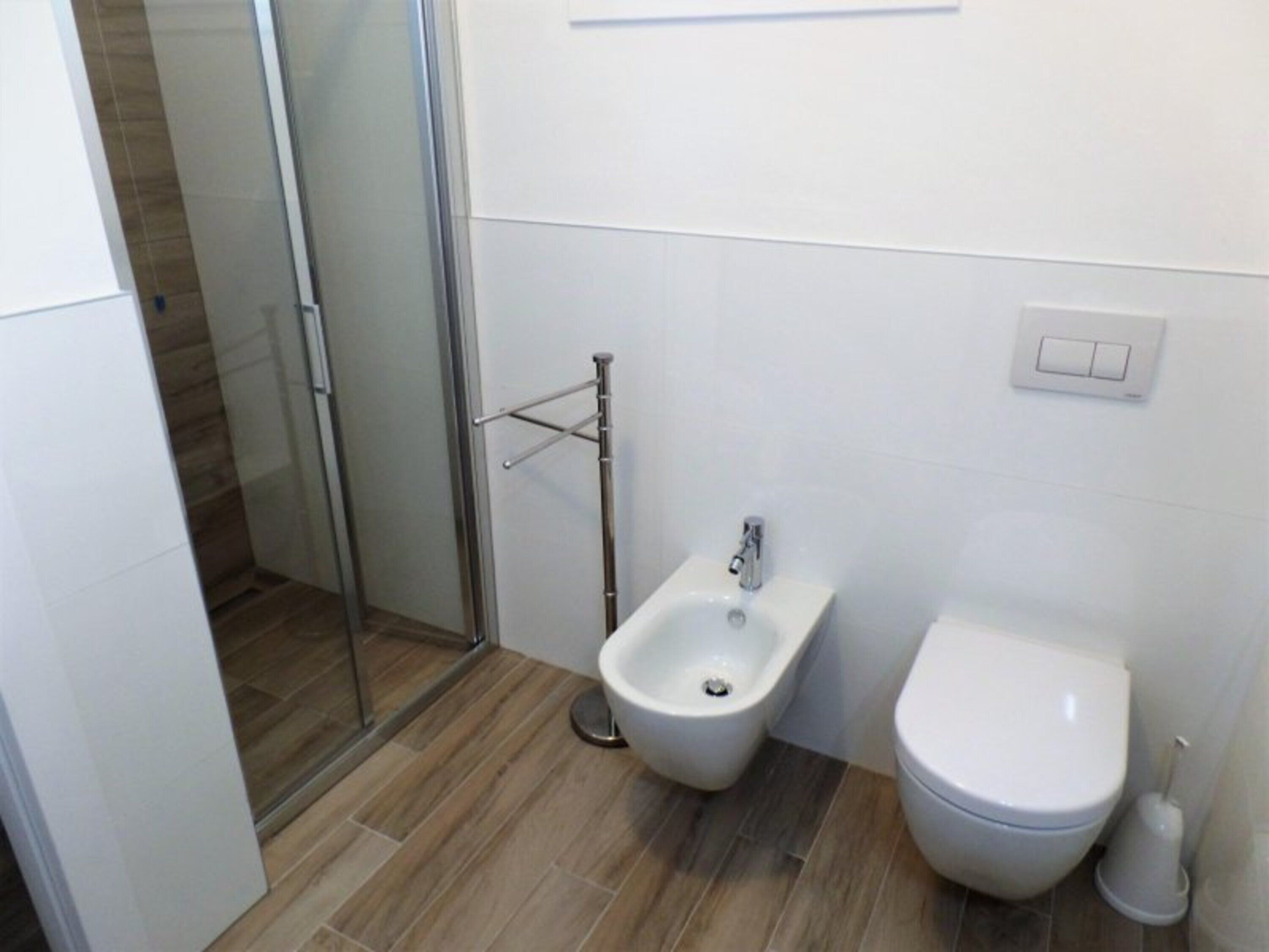 Ein Badezimmer mit integriertem Bidet, Toilette und einer Duschkabine aus Glas.