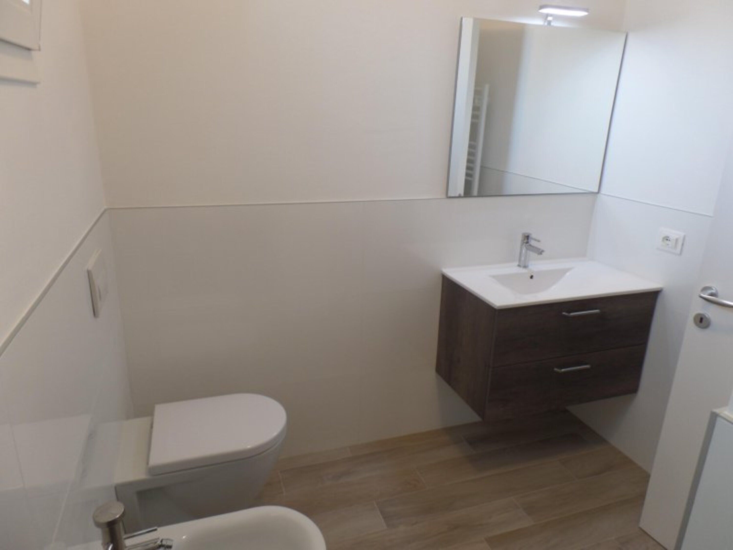 Une petite salle de bain moderne, équipée de toilettes, d’un lavabo et d’un meuble-lavabo.