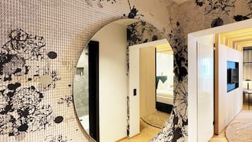 Um quarto com um espelho grande, papel de parede estampado e chão de madeira.