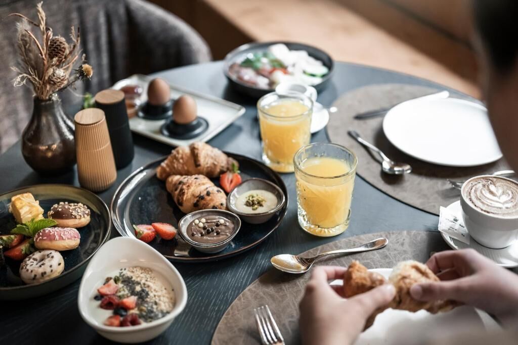 A breakfast setting with pastries, fruits, and beverages on a table.