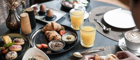 A breakfast setting with pastries, fruits, and beverages on a table.