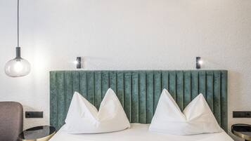A hotel room with a bed, two bedside tables, a chair, and a hanging light fixture.