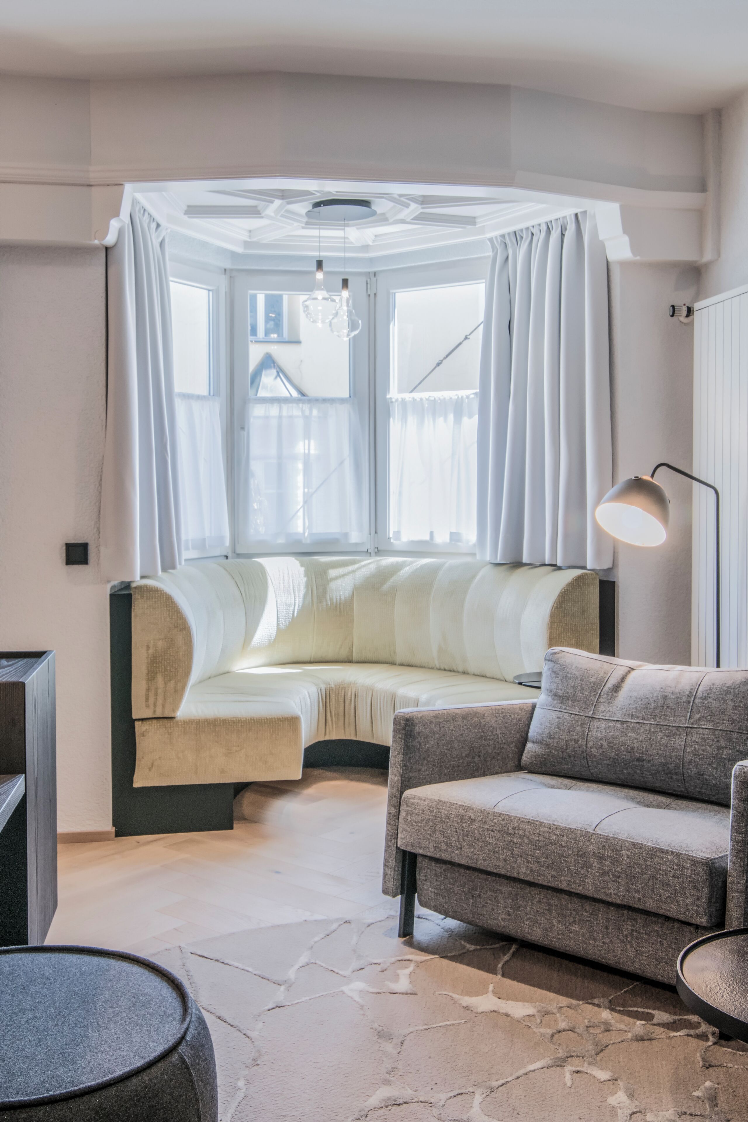 A cozy room with a curved sofa, a round table, and a lamp.