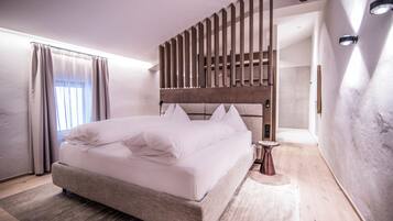 Une chambre à coucher moderne avec un grand lit, une tête de lit en bois, une table de chevet et une fenêtre avec des rideaux.