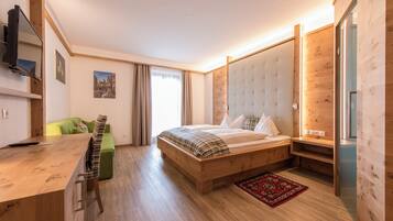 Ein modernes Schlafzimmer mit einem hölzernen Bett, einem Schreibtisch, einem grünen Sofa und einem großen Fenster mit Vorhängen.