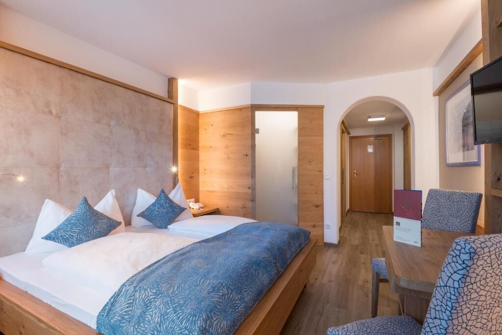 Une chambre à coucher comprenant un lit, une table de chevet et un bureau avec des chaises.