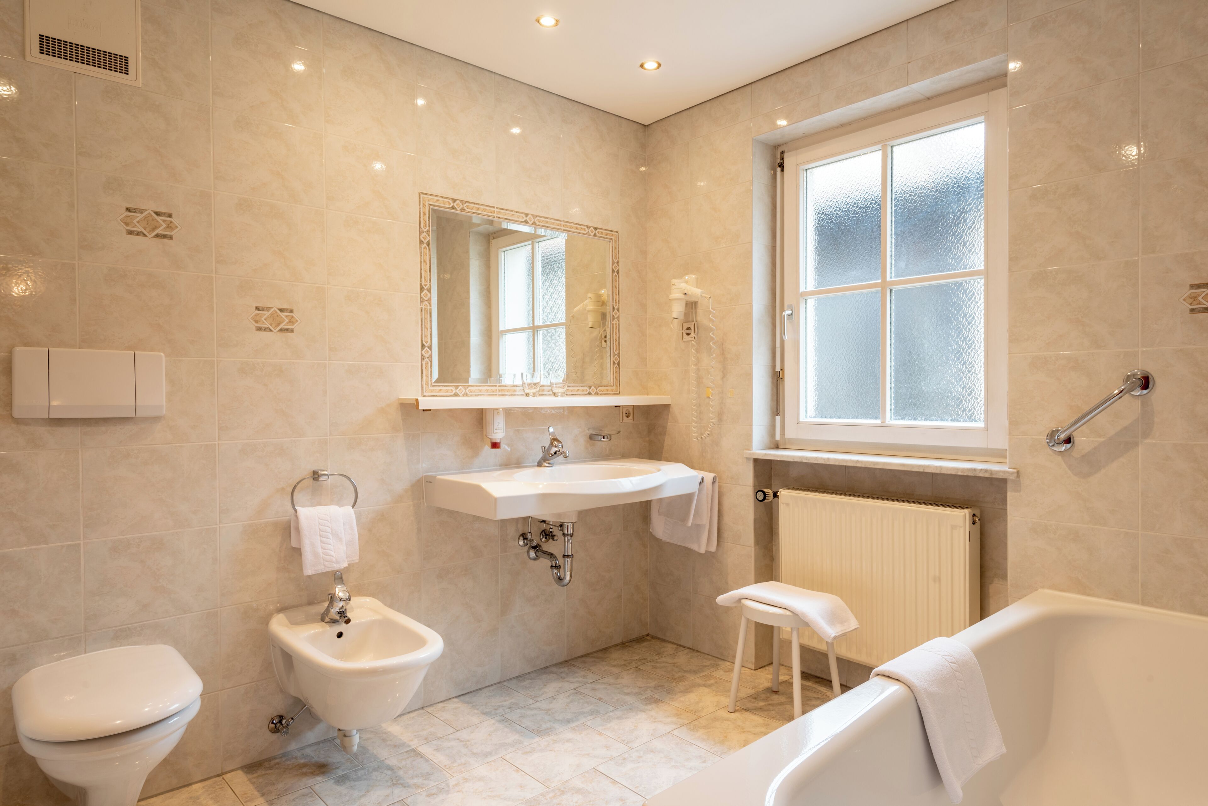 Ein modernes Badezimmer mit Toilette, Bidet, Waschbecken und Badewanne.