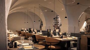 A restaurant with round tables, chairs, and hanging pendant lights.