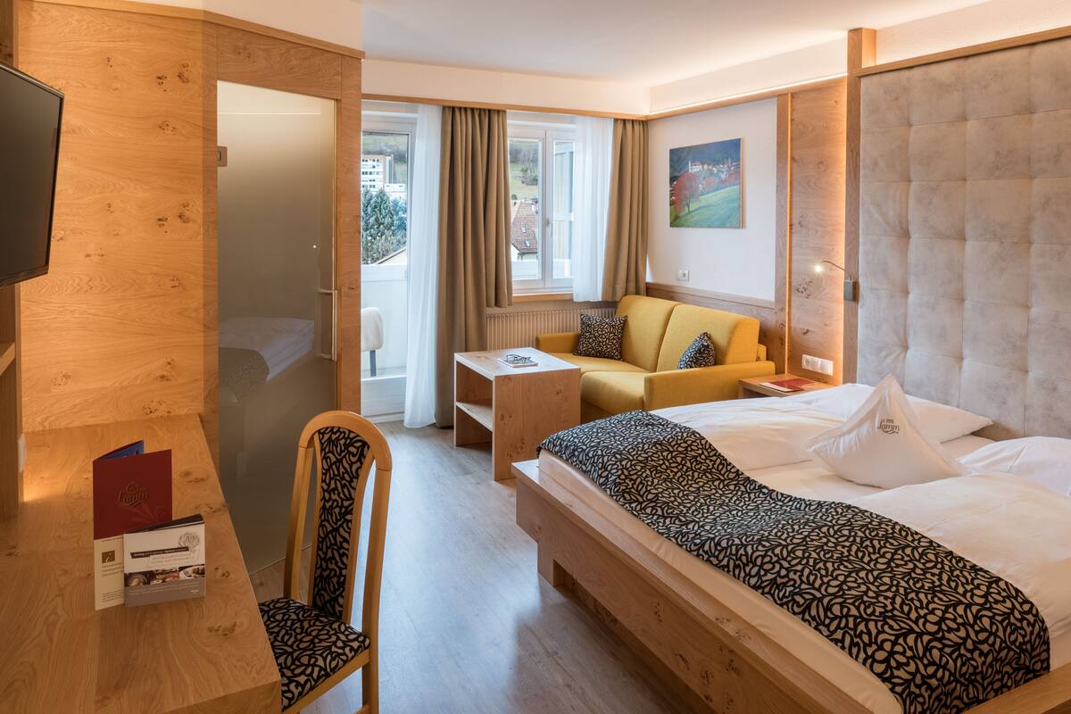 Habitación de hotel con cama, sofá, escritorio, silla y televisión.