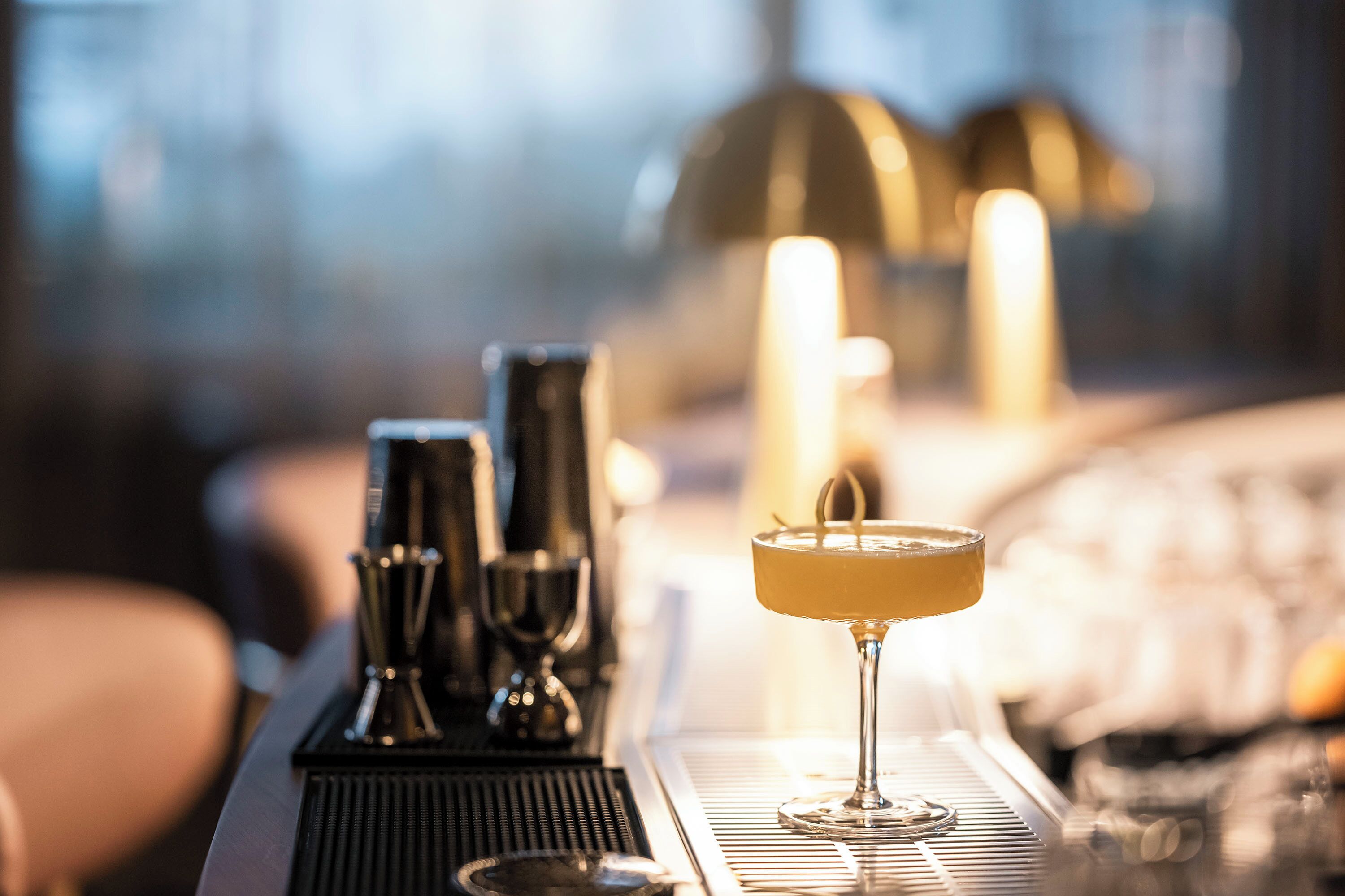 A bar area with a cocktail glass, bar tools, and candles.