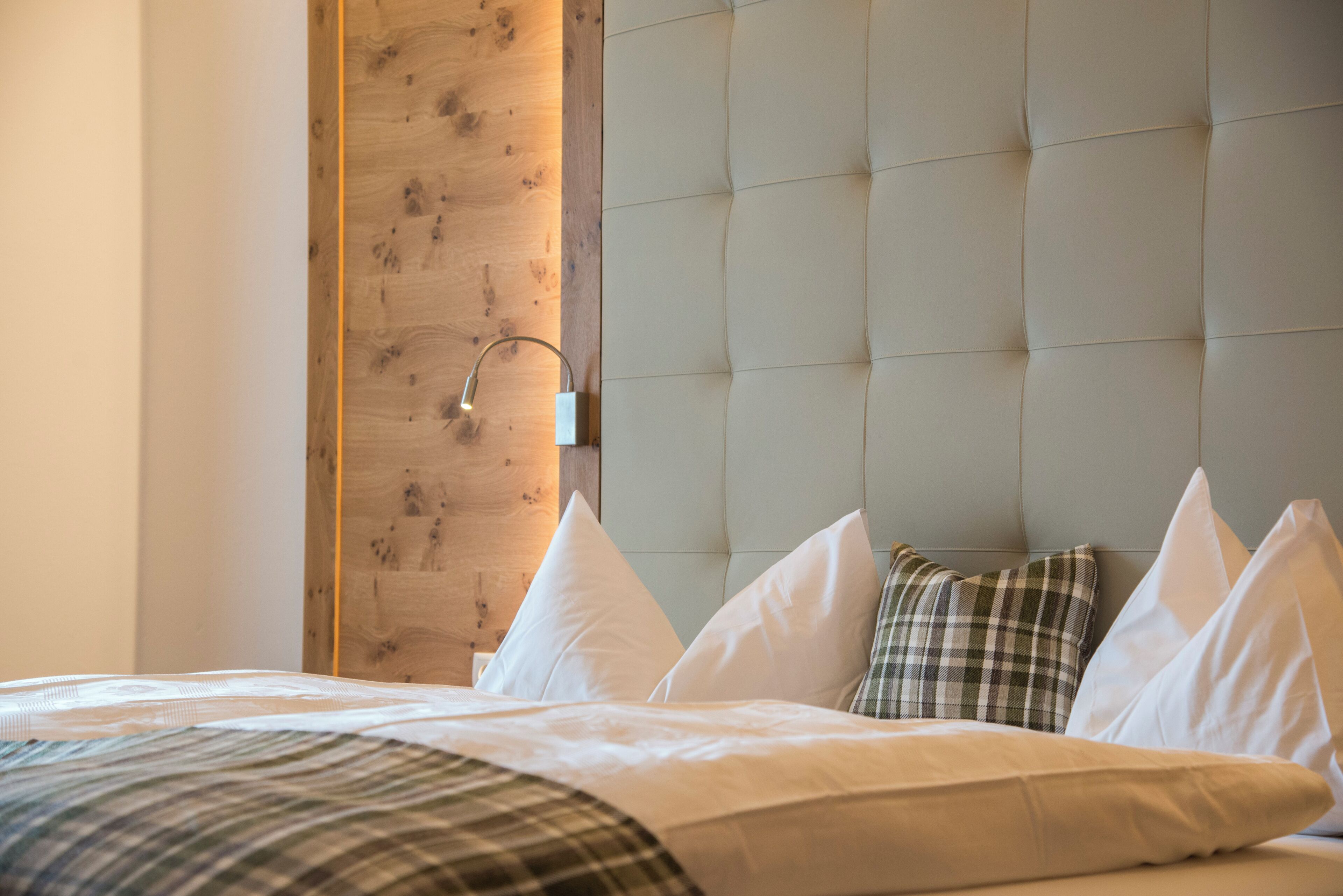 Una habitación de hotel con una cama, una pared decorativa de madera y un cabecero acolchado.