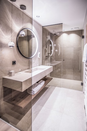 A modern bathroom with a glass-enclosed shower, a double sink vanity, and a large mirror.
