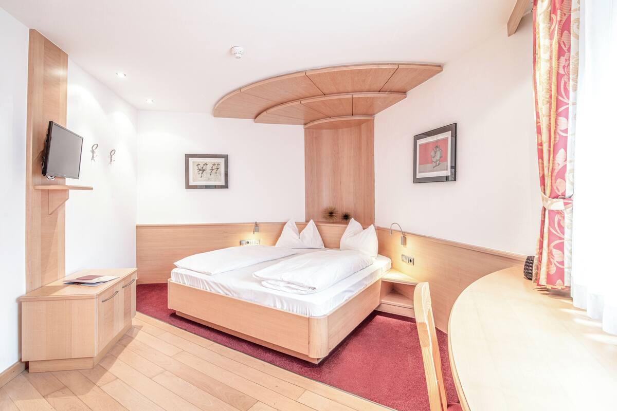 Una habitación de hotel moderna con una cama grande, mesitas de noche, un televisor y obras de arte en las paredes.