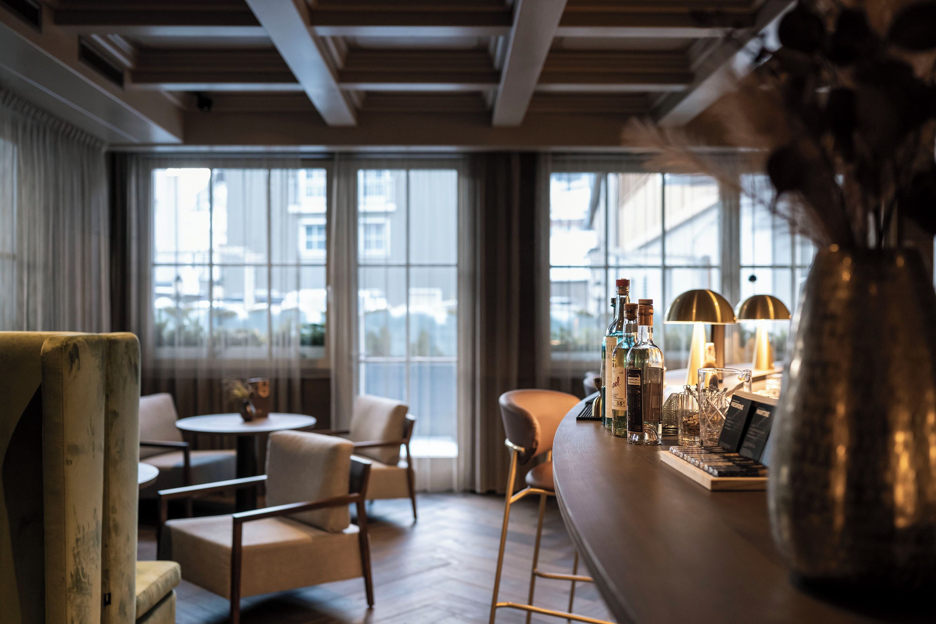 A bar area with a bar stool, a round table, and a vase with flowers.