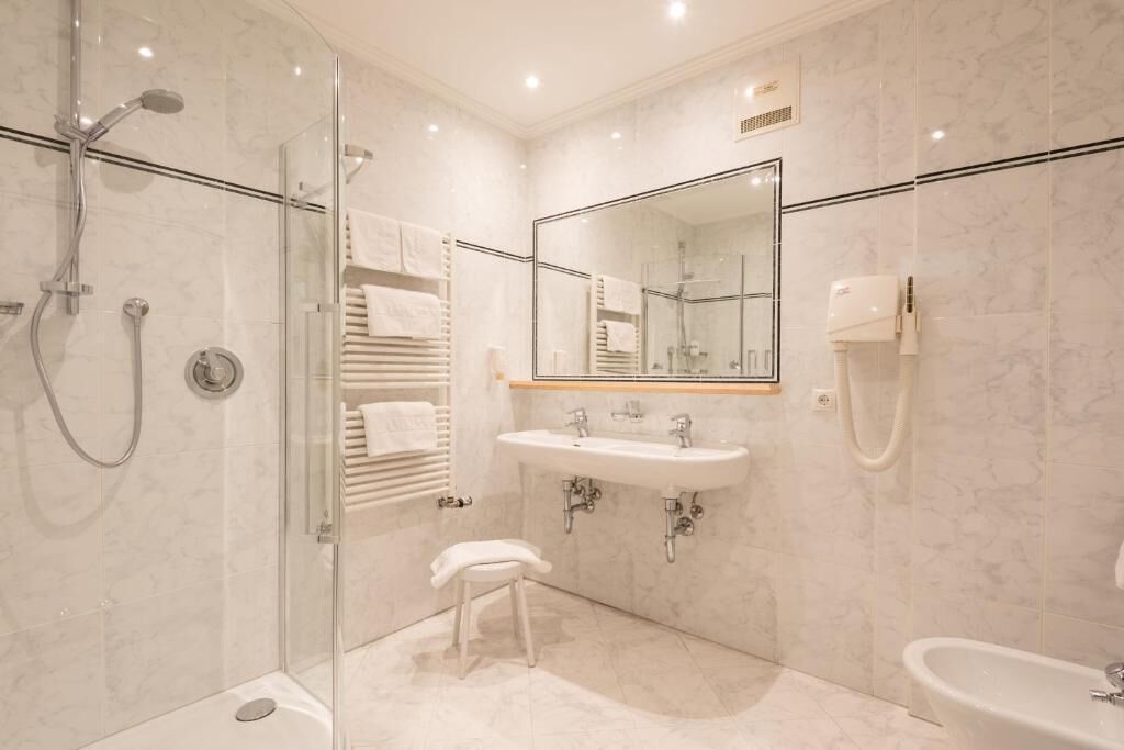 A modern bathroom with a glass-enclosed shower, a sink, a mirror, and a bathtub.