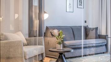 A modern living room with a grey sofa, a round coffee table with a plant, and a patterned rug.