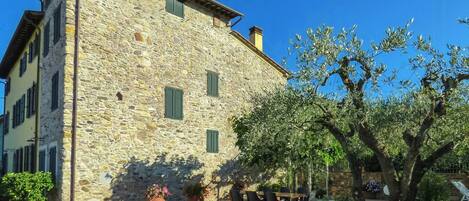 A stone building with a gravel driveway, outdoor seating, and a tree.