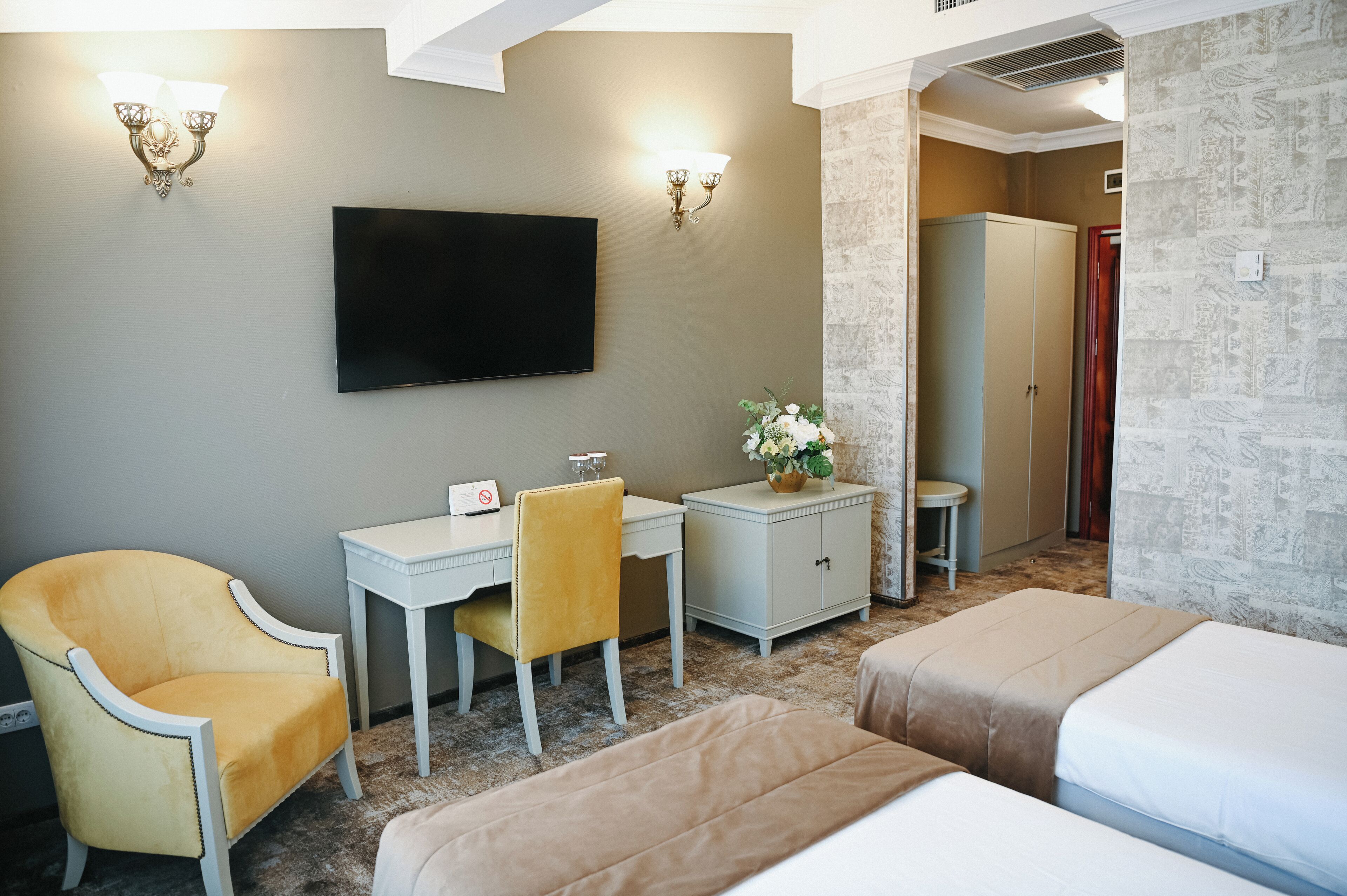 A hotel room with a bed, a desk, a chair, a television, and a wardrobe.