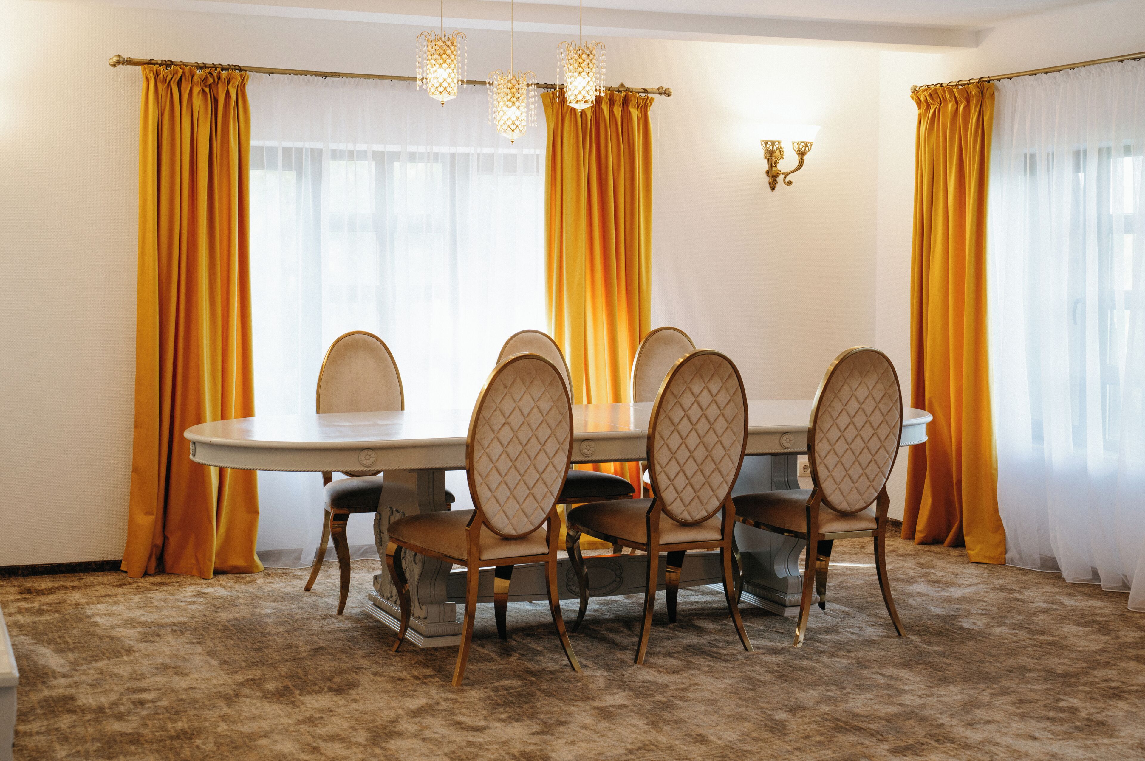 A dining room with a round table, six chairs, and yellow curtains.