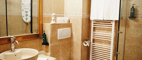 Une salle de bain équipée d’un lavabo, de toilettes, d’une douche et d’un porte-serviettes.