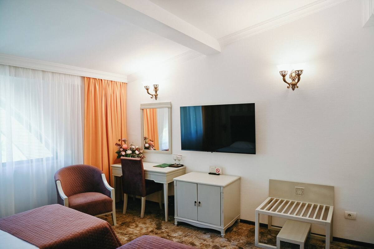 Una habitación de hotel con cama, escritorio, silla, televisor y una mesita.