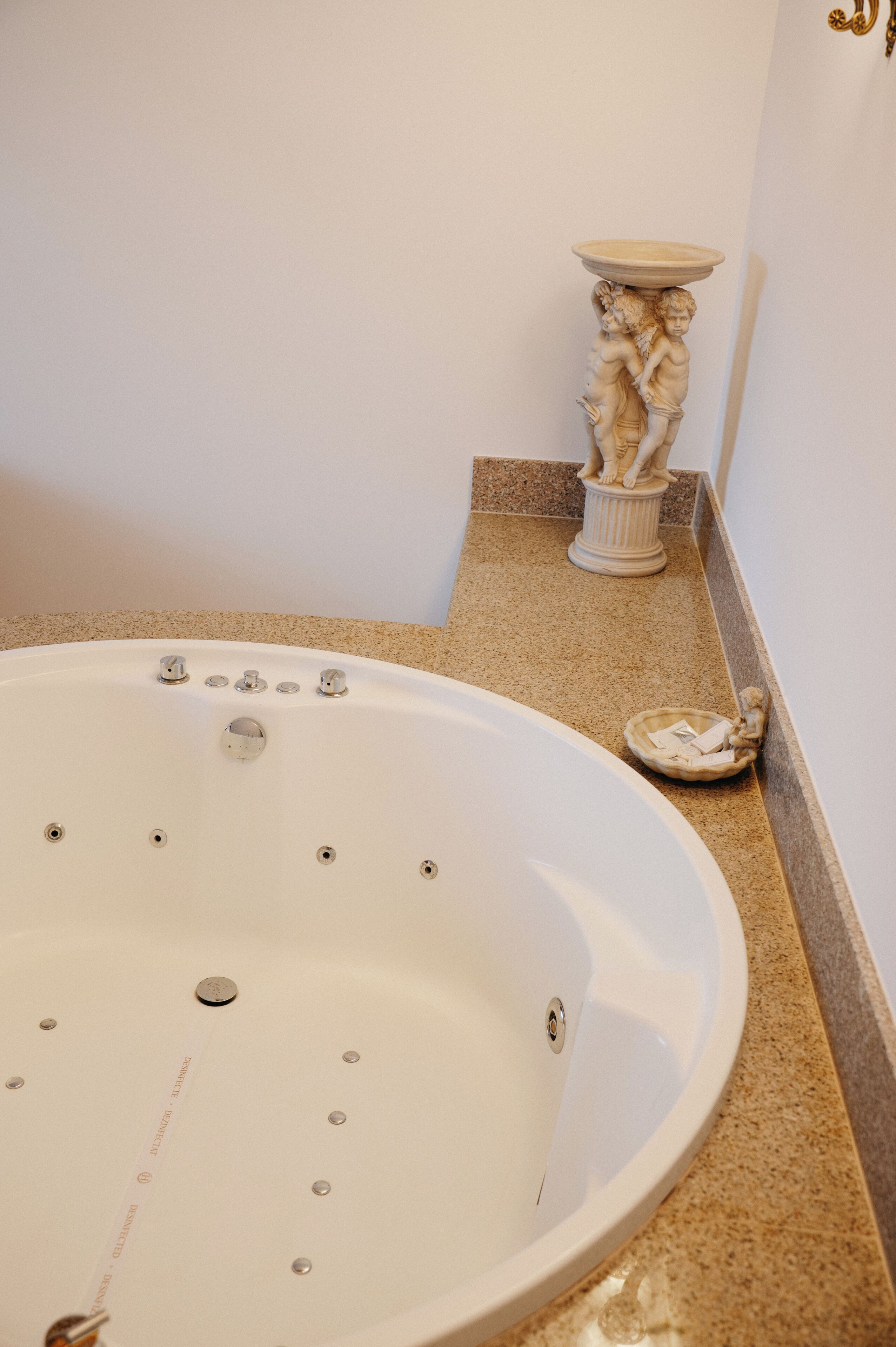 Ein Badezimmer mit einer großen Badewanne, einer Marmorplatte und einer Zierstatue.