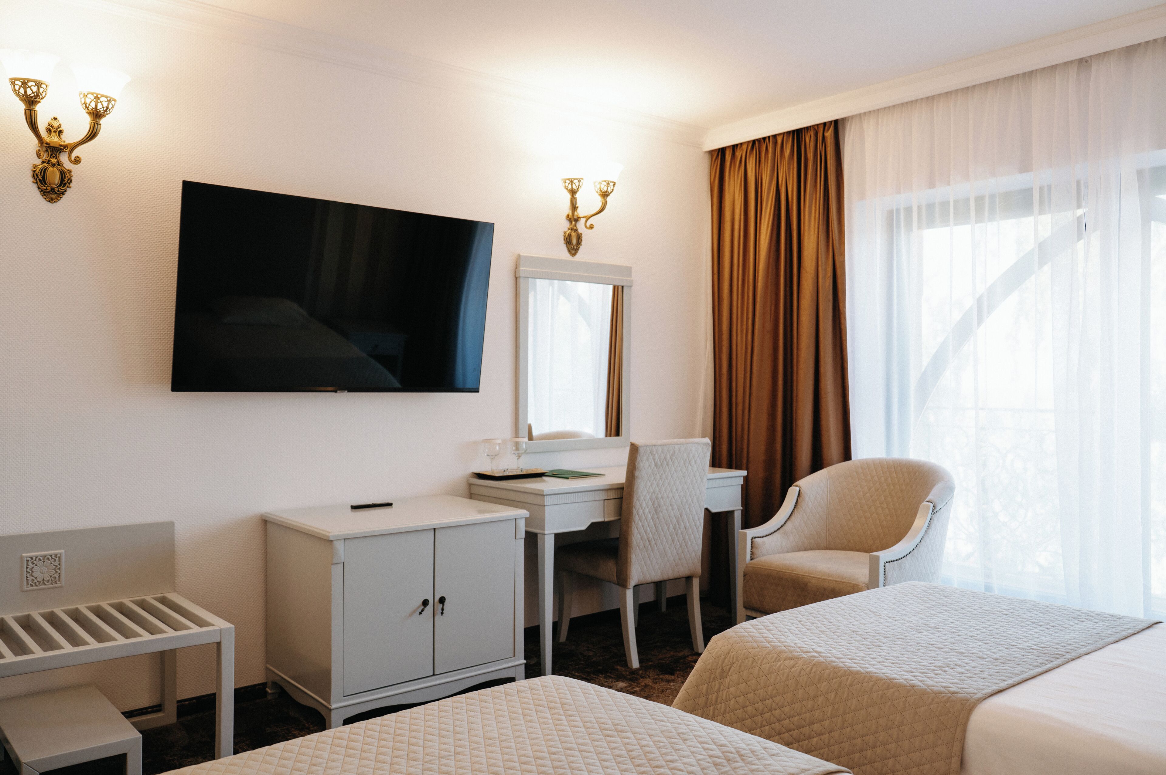 Ein Hotelzimmer mit Bett, Schreibtisch, Stuhl, Fernseher und Kleiderschrank.