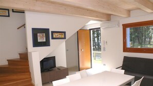 Ein modernes Interieur mit Essbereich, einer Couch, einem Fernseher und einer Treppe.