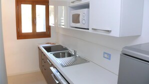 Eine kleine Küche mit Mikrowelle, Spüle und Kühlschrank.