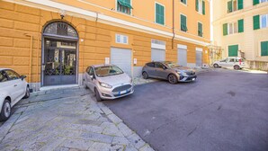 Vista de una calle con coches estacionados, un edificio de fachada amarilla y un toldo cerrado.