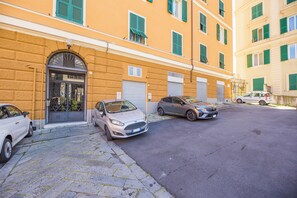 Straßenansicht mit parkenden Autos, einem Gebäude mit gelber Fassade und einem heruntergelassenen Rolltor.