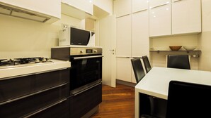 Una cocina moderna con estufa, microondas, horno y un comedor con mesa y sillas.