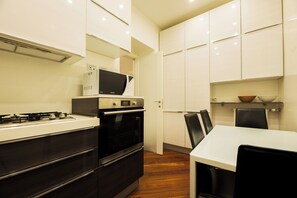 Eine moderne Küche mit Herd, Mikrowelle, Backofen und einem Essbereich mit Tisch und Stühlen.