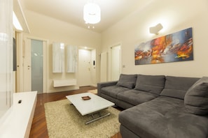 Ein modernes Wohnzimmer mit grauem Sofa, einem weißen Couchtisch und einem Gemälde an der Wand.