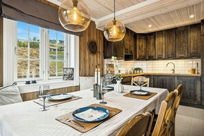 A dining area with a long table, candles, and a view of the outdoors. - Ski-in/ski-out cabin in Holtardalen (Rauland)