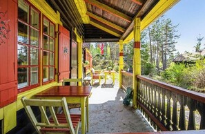 A covered outdoor area with a wooden table and chairs, a railing, and a view of trees and a building in the background. - Historic cabin by the forest in Årnes (Årnes)