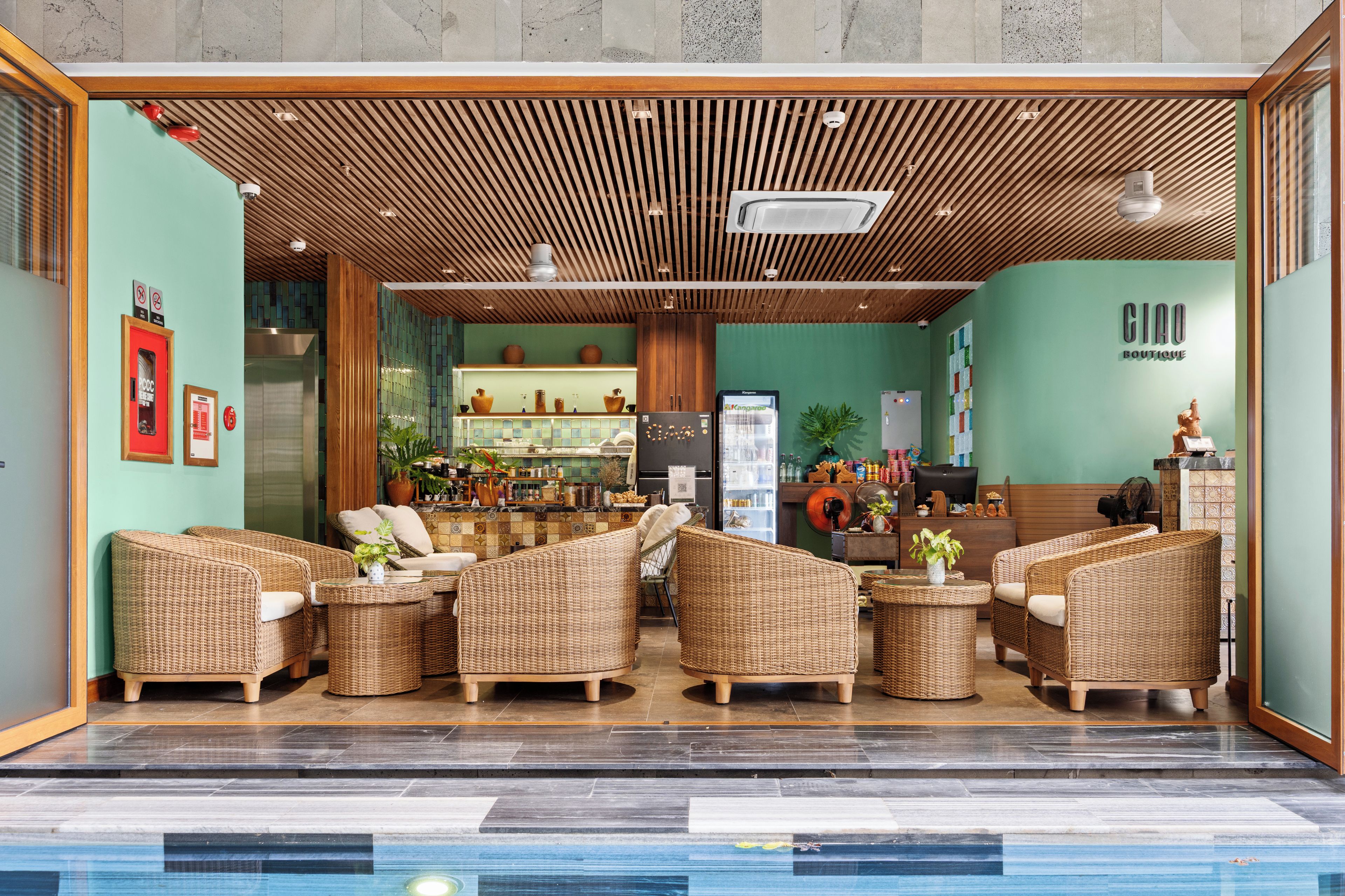 A lobby with wicker furniture, a reception desk, and a wall with a sign reading 'CIAO BOUTIQUE'.