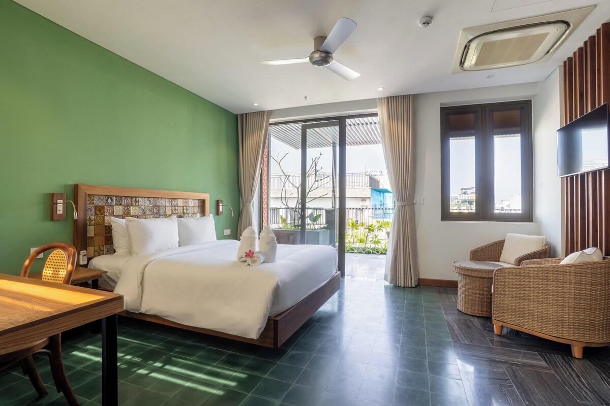 Une chambre d’hôtel comprenant un lit, une table à manger, une chaise, un canapé, un ventilateur de plafond et un téléviseur.