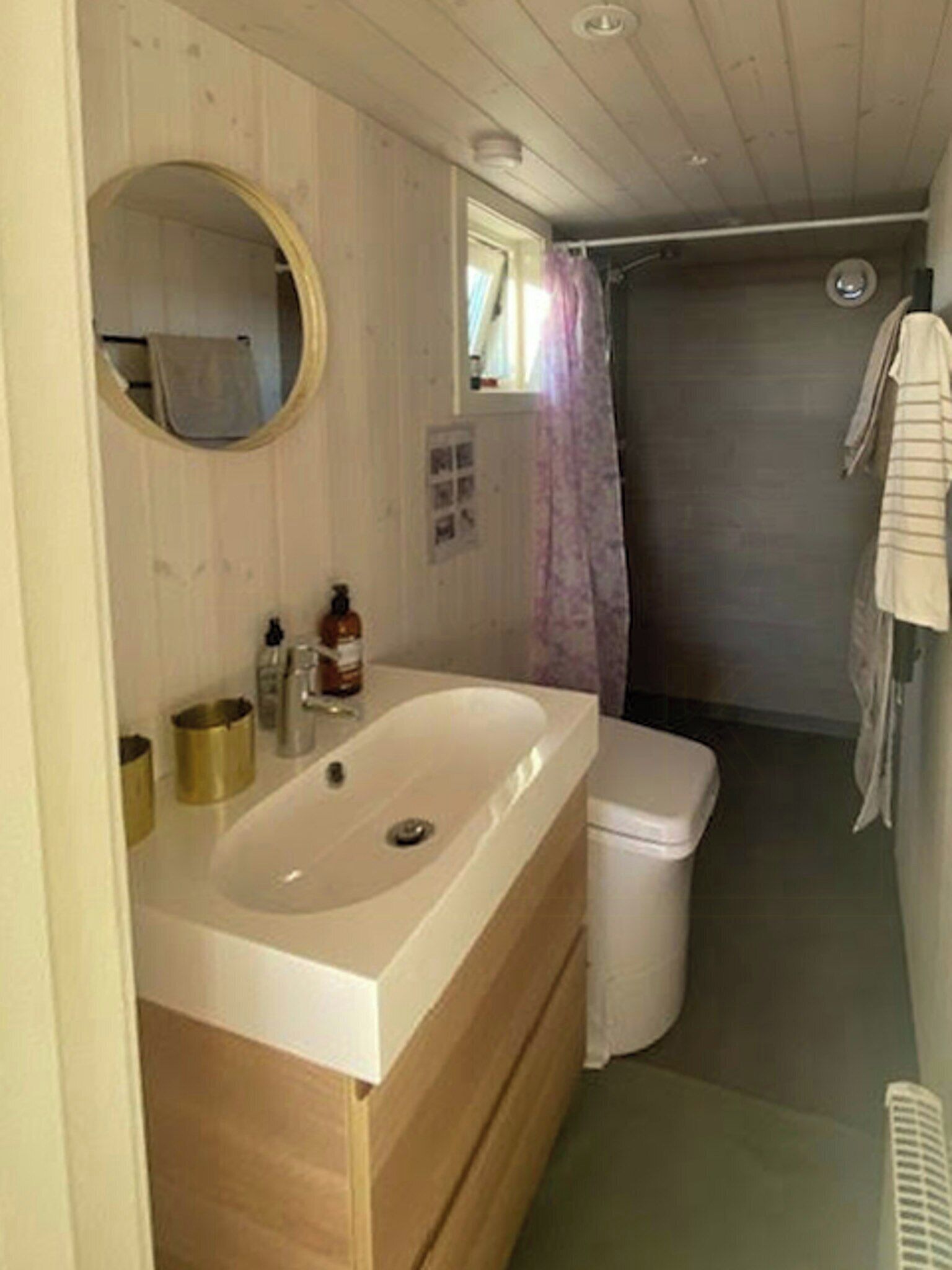 A bathroom with a wooden vanity, a sink, a toilet, and a shower area.