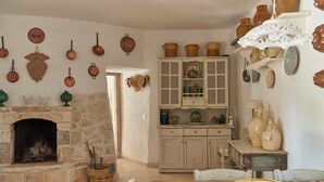 Une cuisine rustique avec une cheminée en pierre, des armoires en bois et divers ustensiles de cuisine.