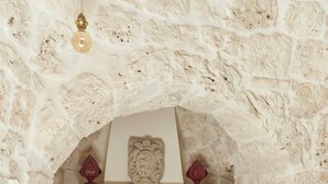 Une cheminée en pierre, agrémentée de deux fauteuils, d’une table et d’une assiette décorative placée au-dessus du foyer.