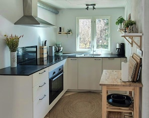 Een keuken met een fornuis, oven, spoelbak en een houten tafel met een kom.