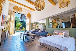 A modern living room with a sofa, coffee table, and a bed with a decorative pillow. - Luxury villa with pool in Baho (Baho)
