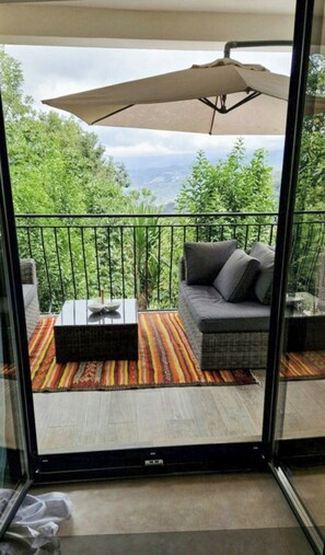 Ein Balkon mit einer Couch, einem Tisch und einem Sonnenschirm.