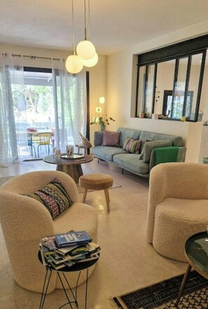 Ein modernes Wohnzimmer mit Sofa, Sesseln, einem Couchtisch und einem Essbereich mit Tisch und Stühlen.