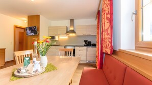 Una cocina moderna con comedor, televisor y ventana con cortinas.
