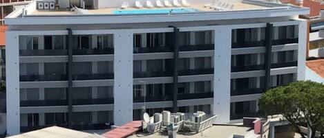 Un edificio de varios pisos con piscina en la azotea y varias terrazas.