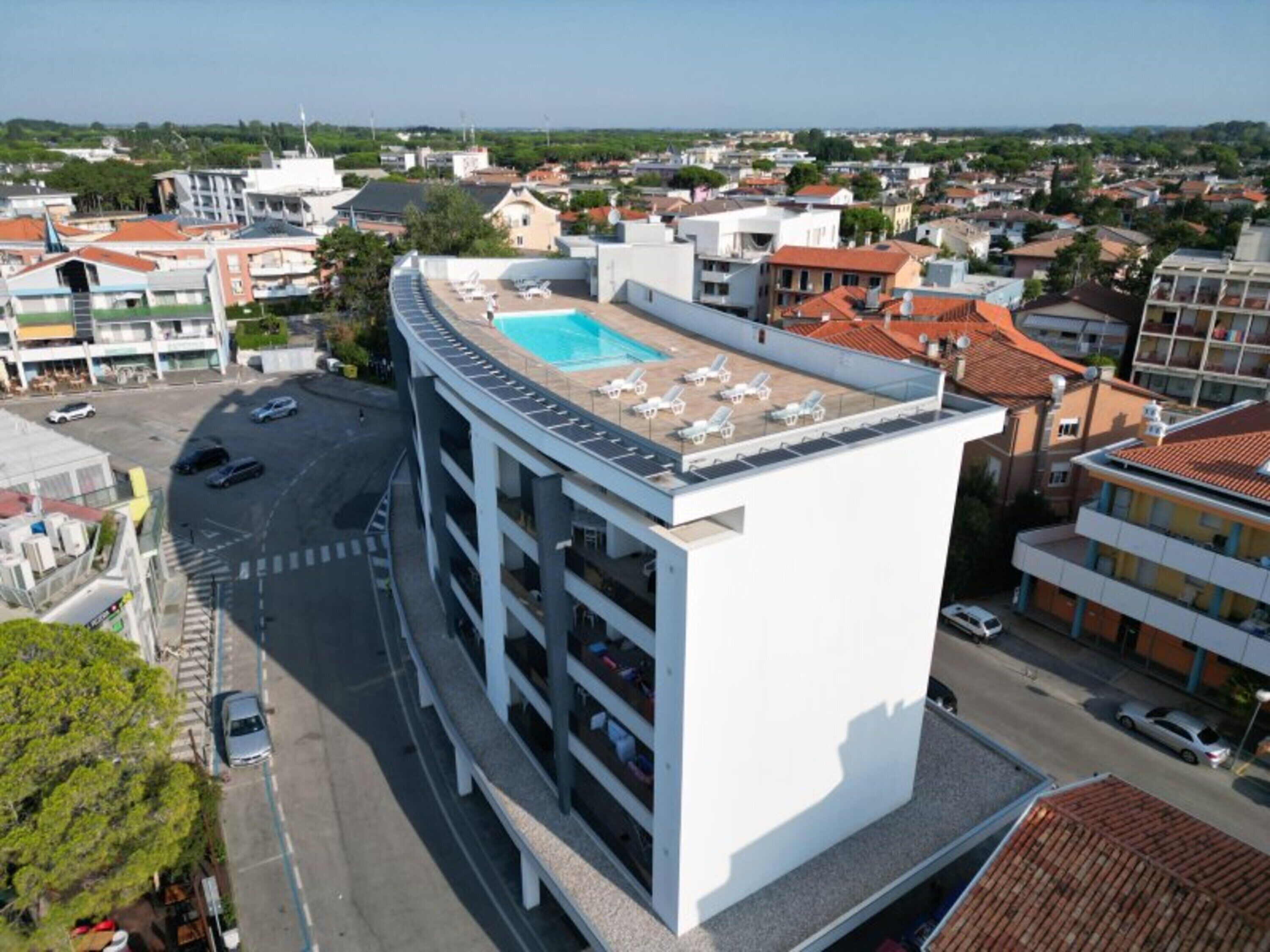 Un immeuble à plusieurs étages doté d’une piscine sur le toit et de chaises longues.