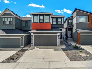 A modern residential area with multiple houses, a driveway, and a well-maintained lawn. - Modern and Cozy 2 bedroom Basement Suite with fully equipped kitchen (Calgary)